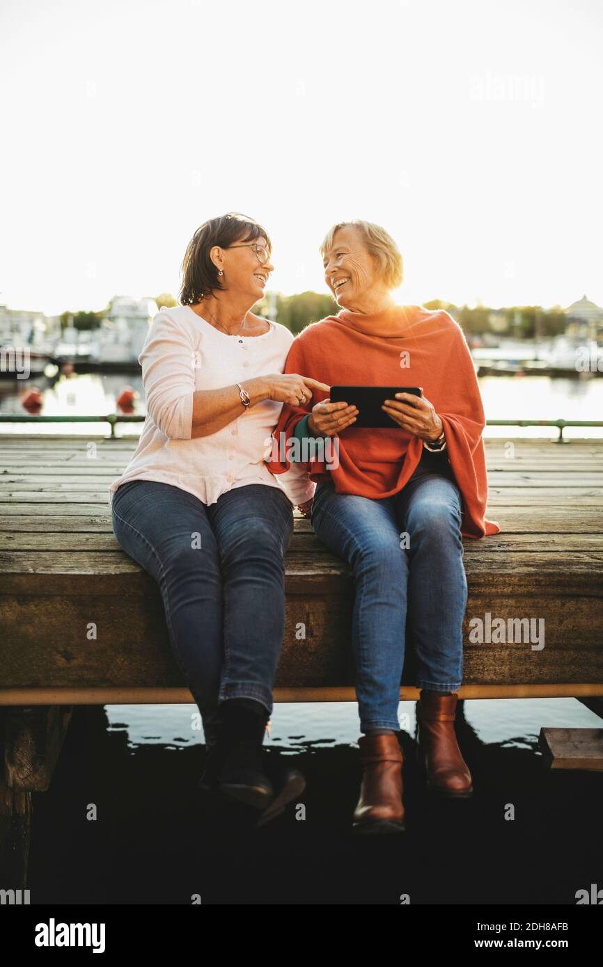 Volle Länge der glücklichen älteren Frauen mit digitalen Tablet auf pier Stockfoto