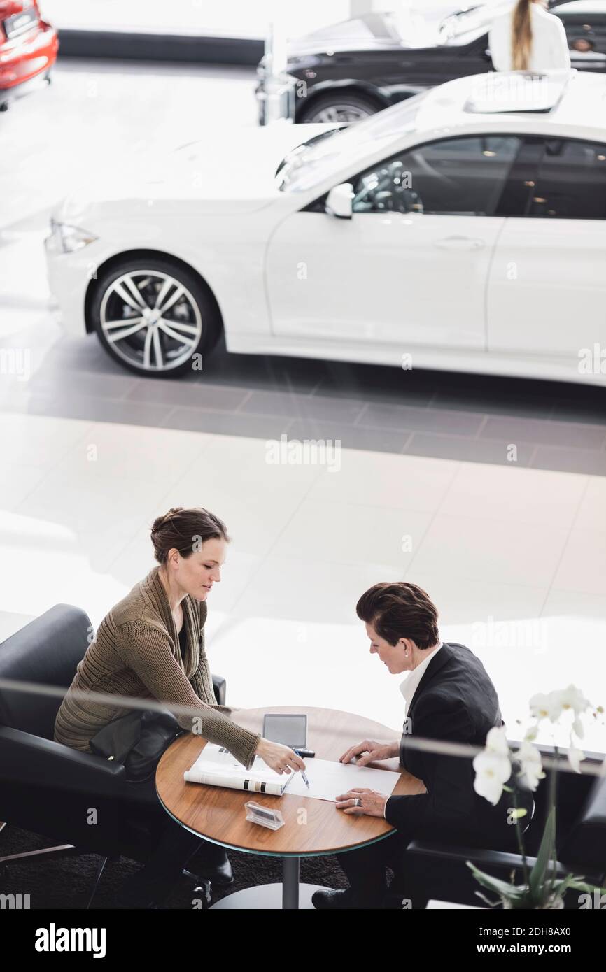 Verkaufsmitarbeiter erklärt dem Kunden das Dokument in einem Autosalon Stockfoto
