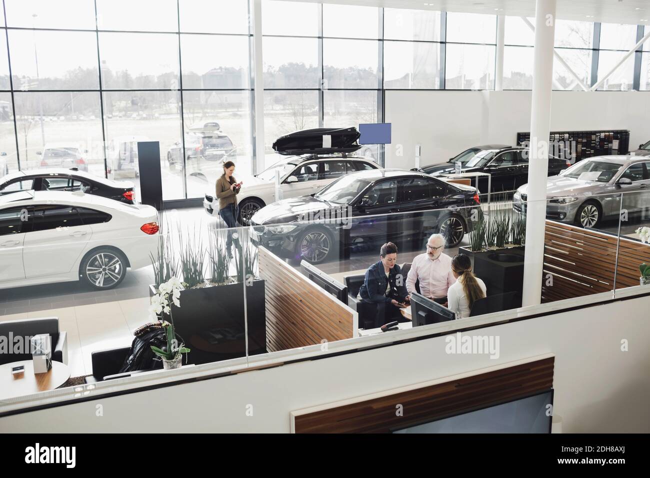 Autoverkäufer, der mit Kunden am Schreibtisch im Ausstellungsraum spricht Stockfoto