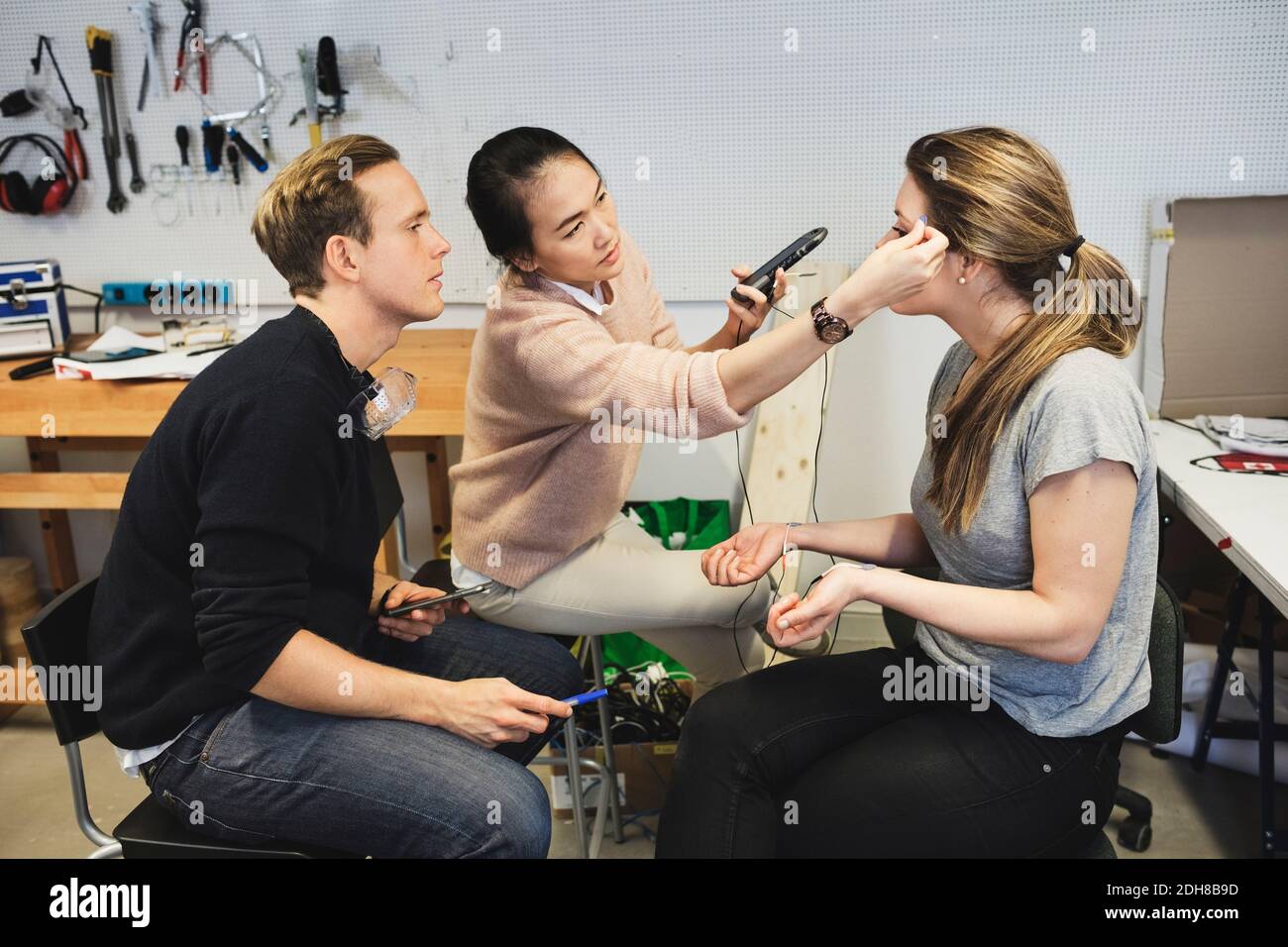 Geschäftsleute überprüfen Workout-App auf Frau in der Werkstatt Stockfoto