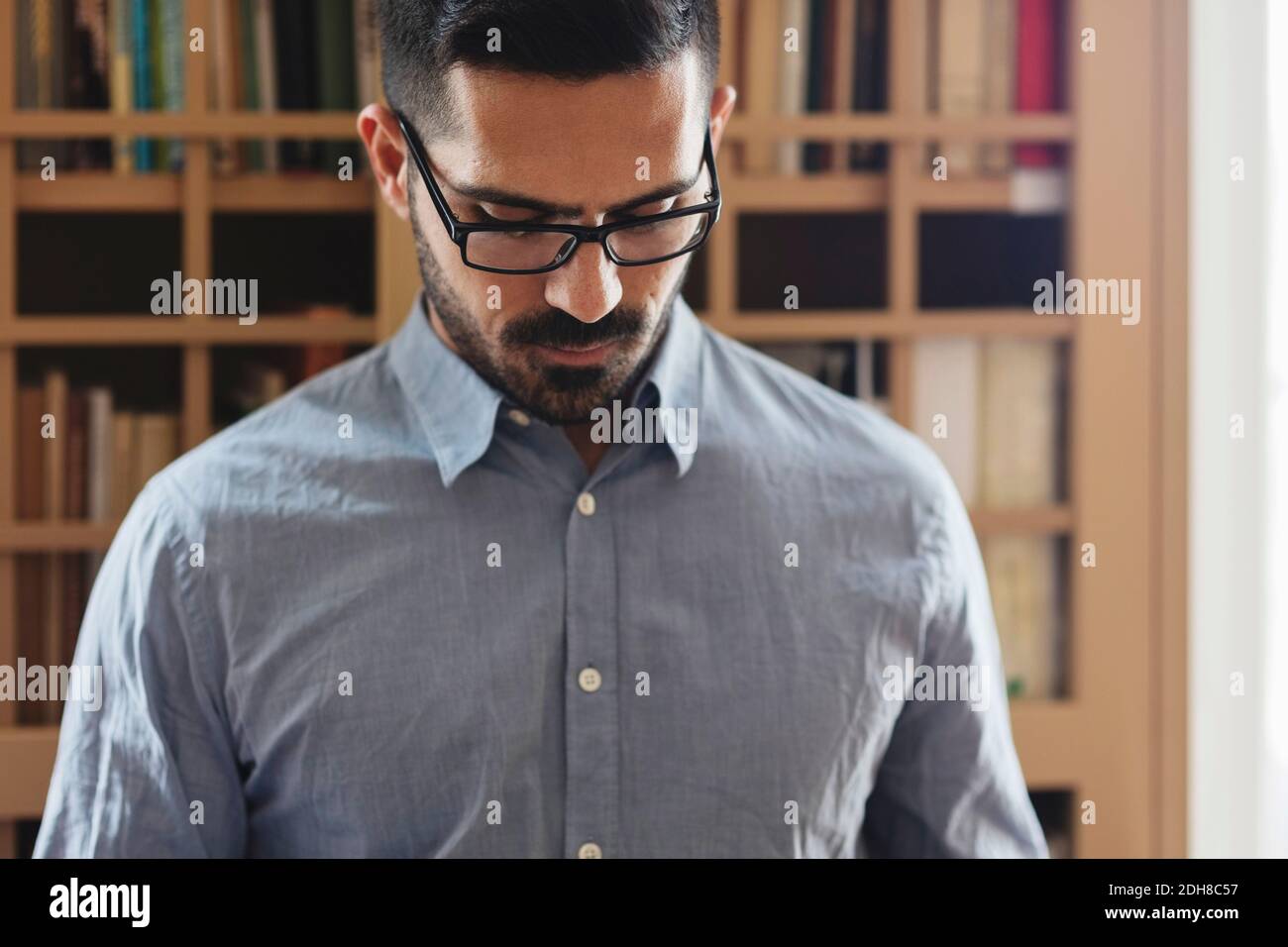 Männlicher Anwalt, der gegen Bücherregal hinunterschaut Stockfoto