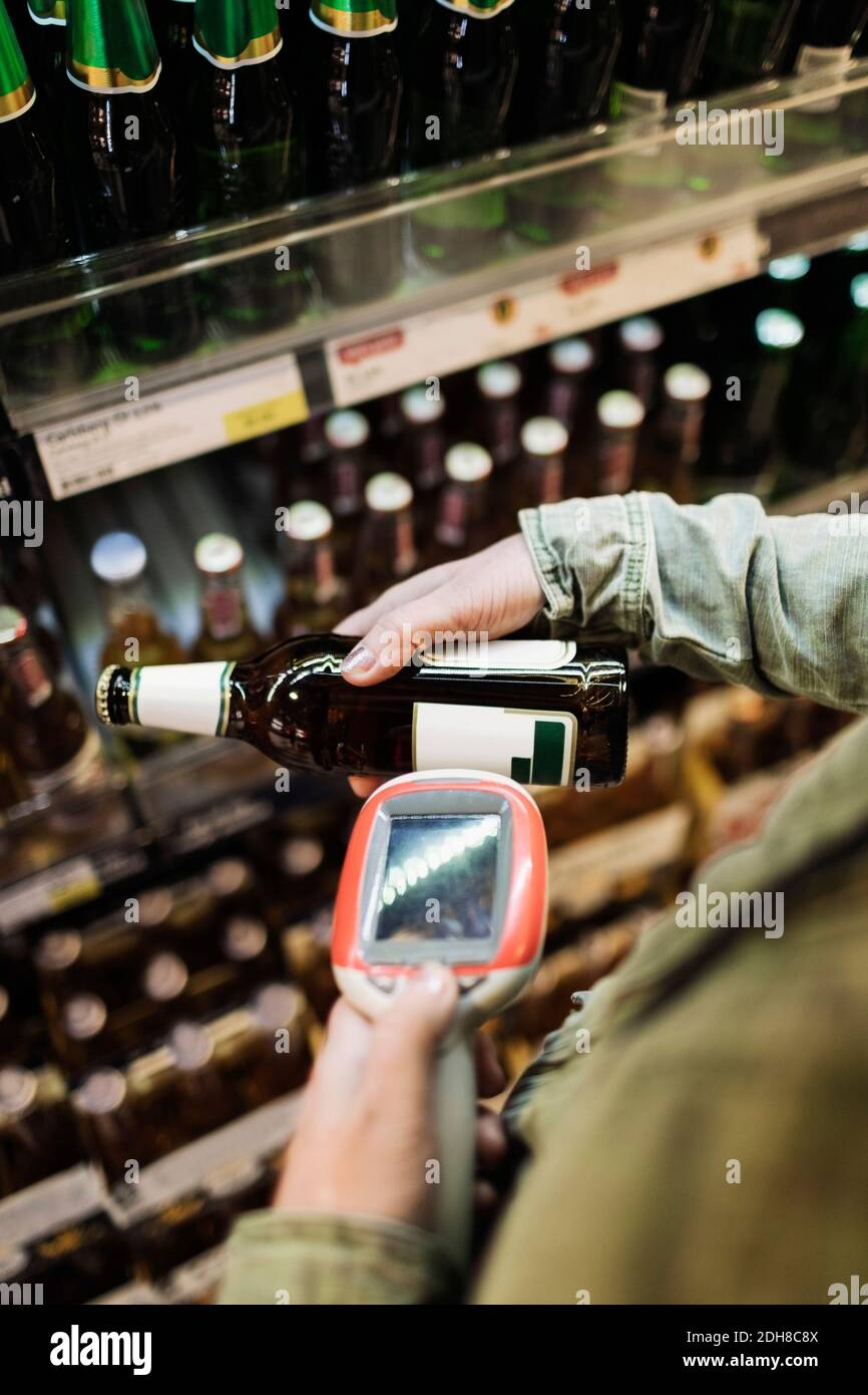 Zugeschnittenes Bild einer Kundin, die Bierflasche im Supermarkt scannt Stockfoto