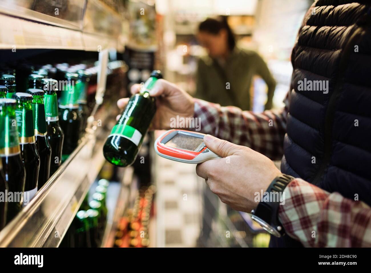 Mittelteil des männlichen Kunden Scannen Bierflasche im Supermarkt Stockfoto