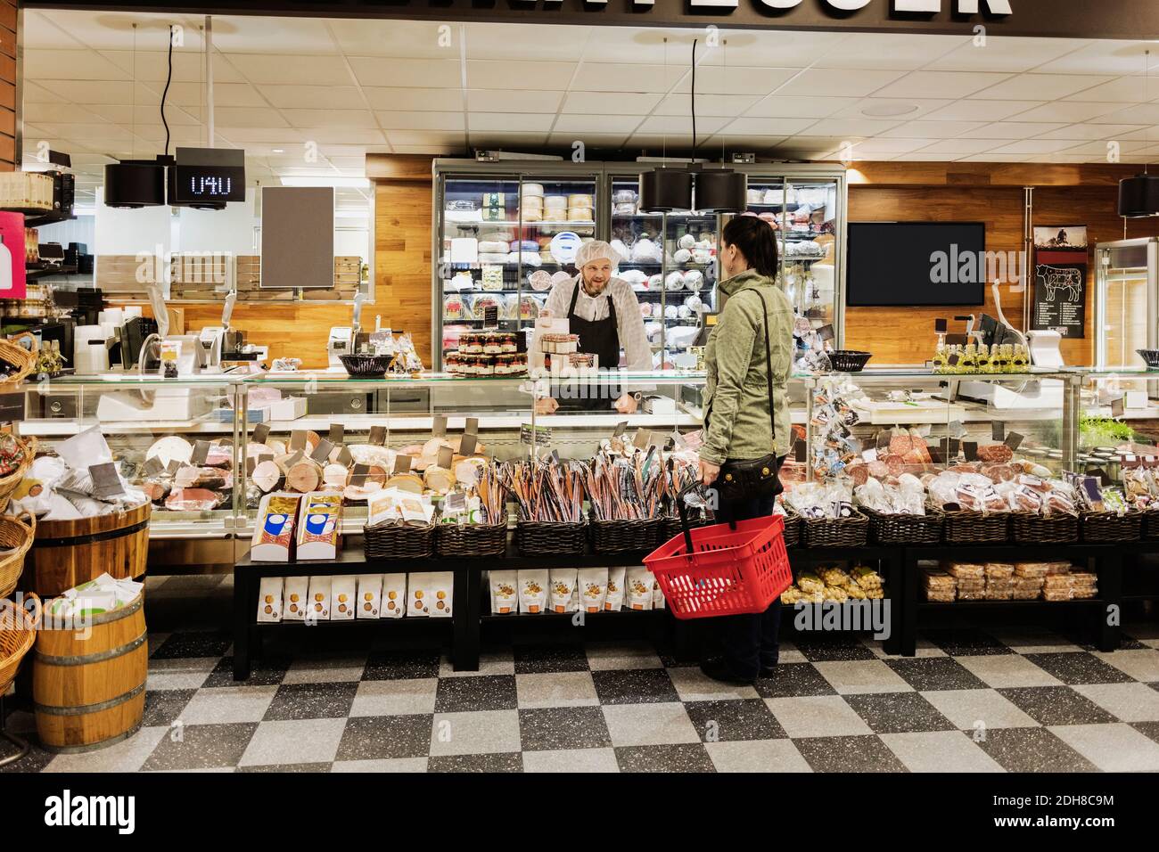 Verkäuferin hilft Frau, während sie im Supermarkt steht Stockfoto