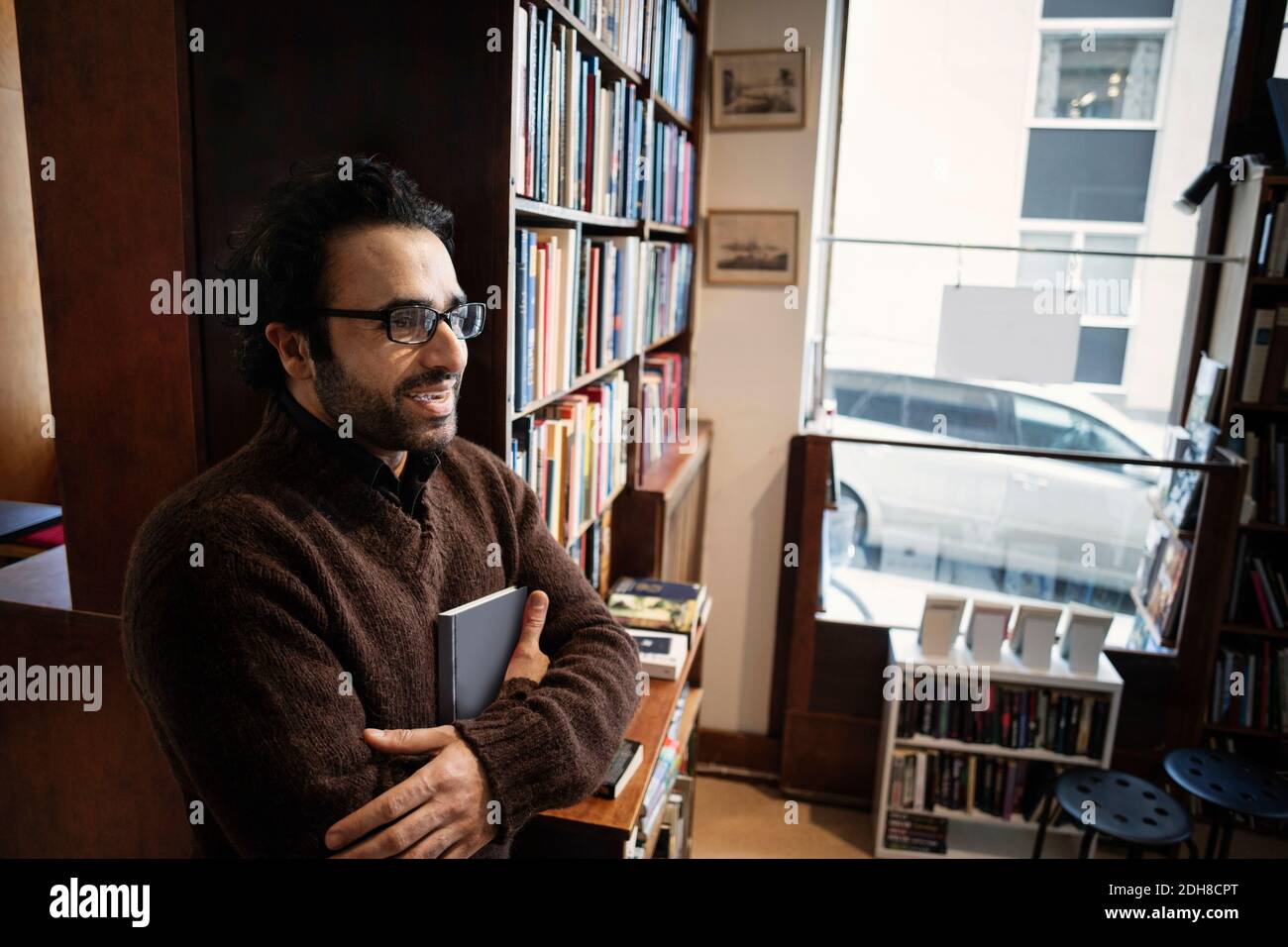 Lächelnder Mann hält Buch im Antiquitätengeschäft Stockfoto