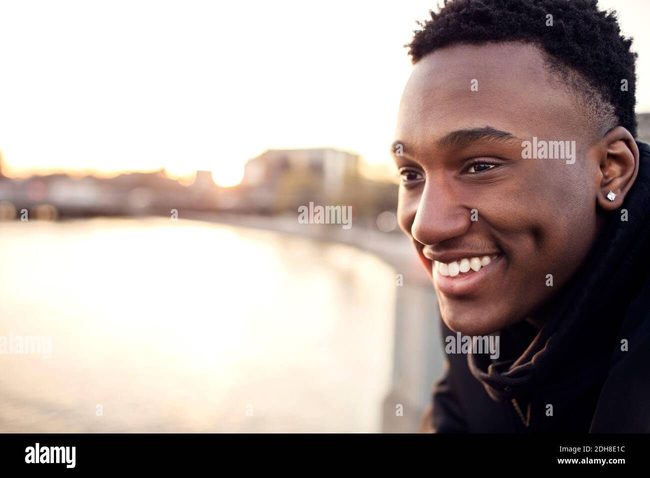 Nahaufnahme eines lächelnden Teenagers gegen den Kanal in der Stadt Stockfoto