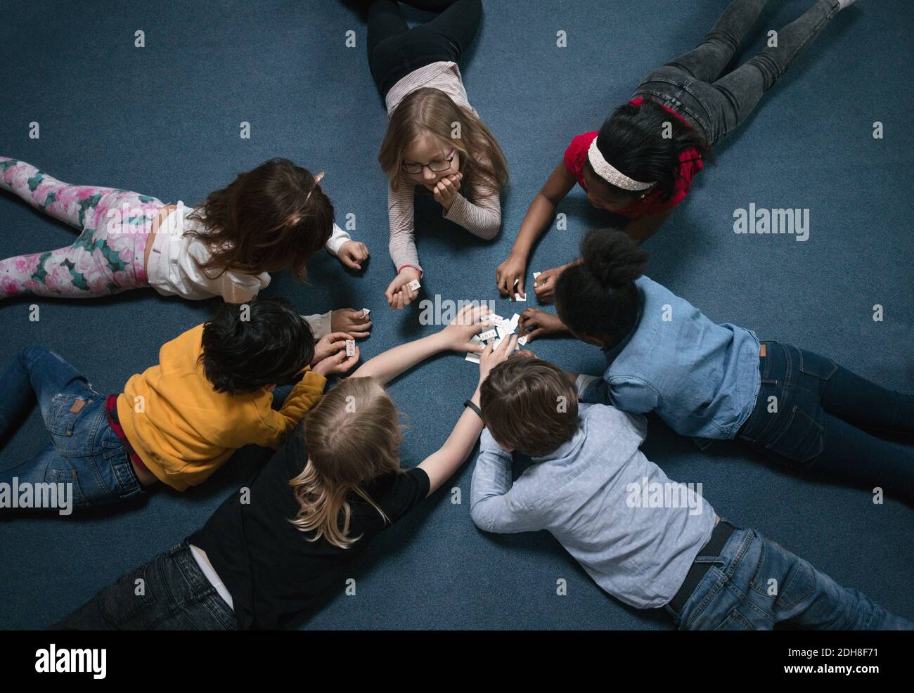 Direkt über der Aufnahme von spielenden Kindern, die auf dem Boden liegen In der Schule Stockfoto