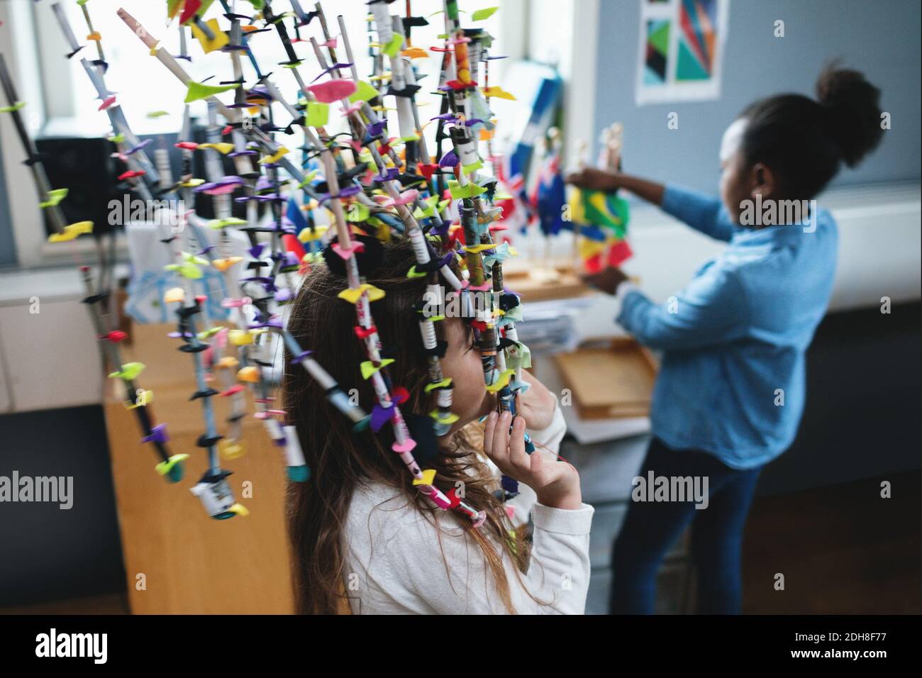 Mädchen spielen mit Dekoration, während Freund Blick auf Fahnen in Schulungsraum Stockfoto