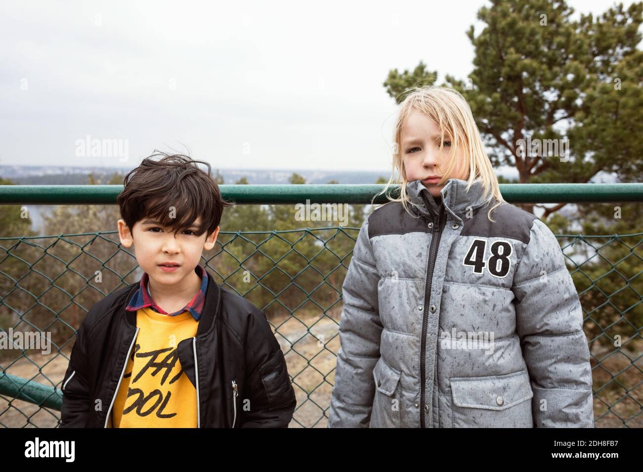 Portrait von Schülern in warmer Kleidung, die gegen den Zaun stehen Stockfoto