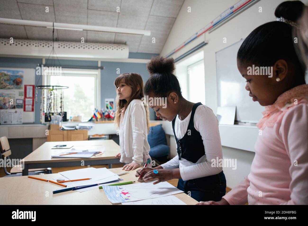Studentinnen, die im Klassenzimmer am Schreibtisch sitzen Stockfoto