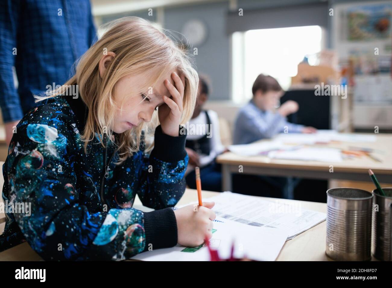 Konzentriertes Mädchen, das am Tisch im Klassenzimmer studiert Stockfoto