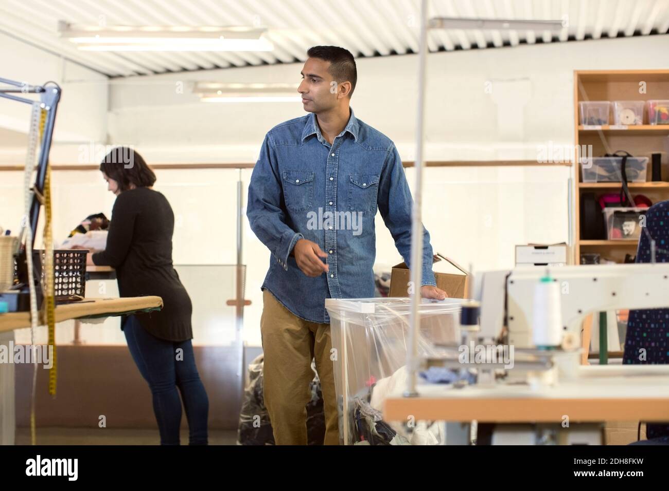 Mann, der bei einem Plastikbehälter steht, während er freiwillig in der Werkstatt arbeitet Stockfoto