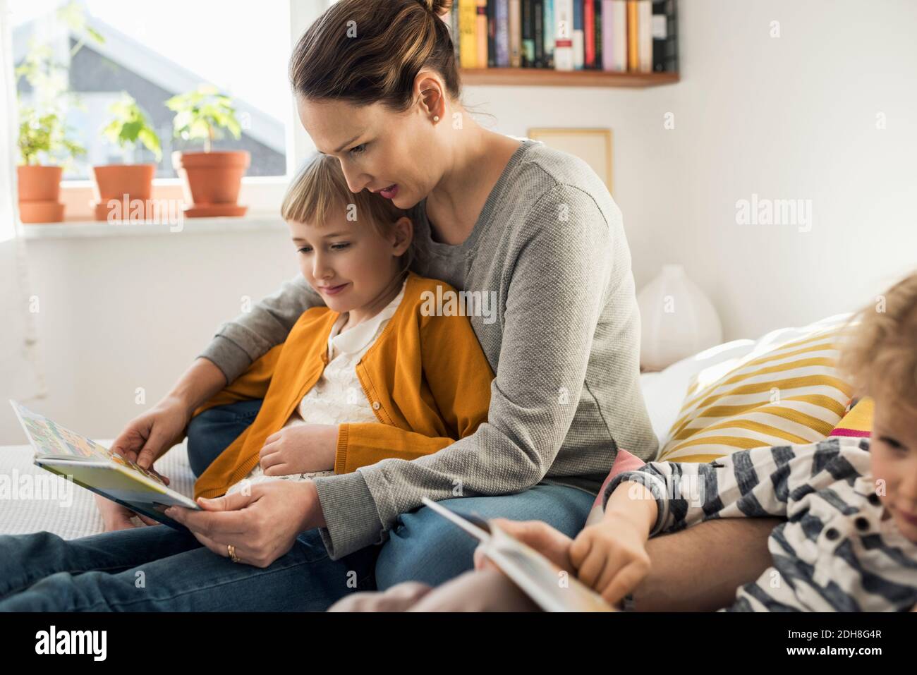 Mutter liest Bildbücher zu Hause für Tochter Stockfoto