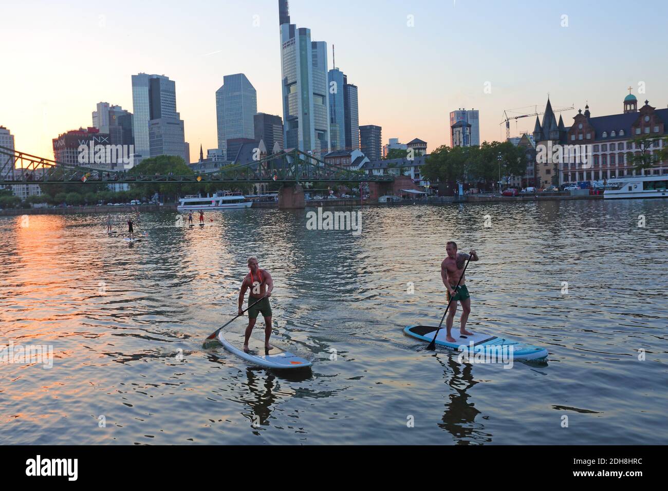 Zwei Leute, die mit der Frankfurter Main Skyline, Hessen, ein Stand-up-Paddle-Boarding machen. Stockfoto