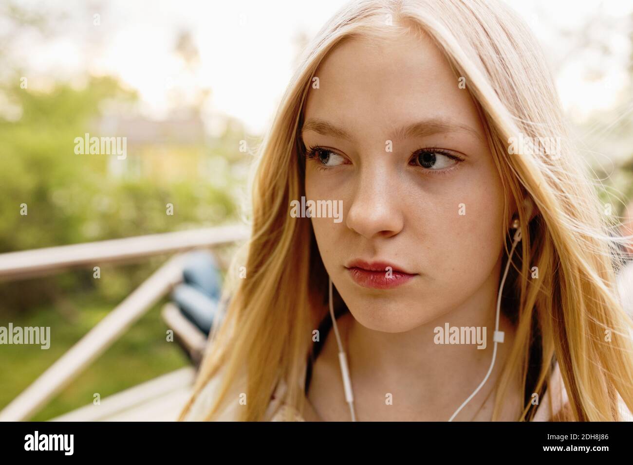 Nachdenkliches Teenager-Mädchen, das Musik im Hof hört Stockfoto