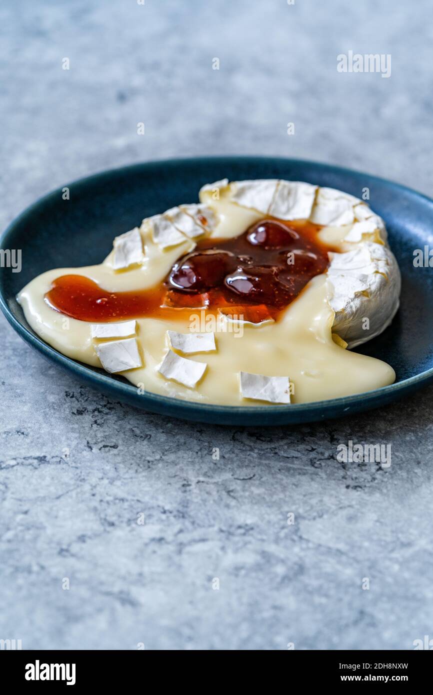 Gebackenes Brie-Käse-Dessert mit Erdbeermarmelade. Marmelade Geschmolzen Camembert. Traditionelles Bio-Dessert. Stockfoto