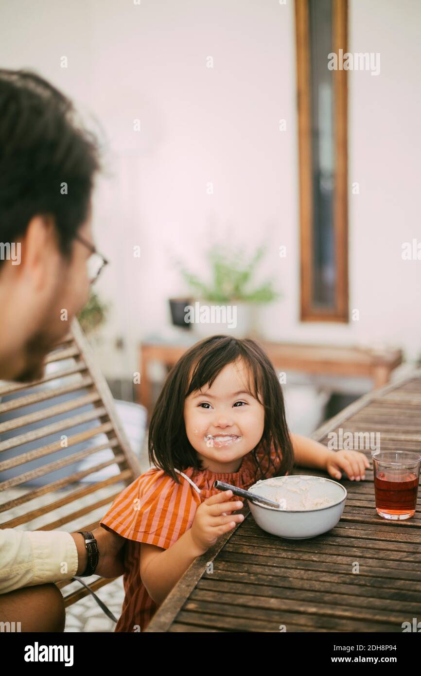 Smiling Down Syndrom Tochter beim Essen Vater zu sehen Am Esstisch Stockfoto