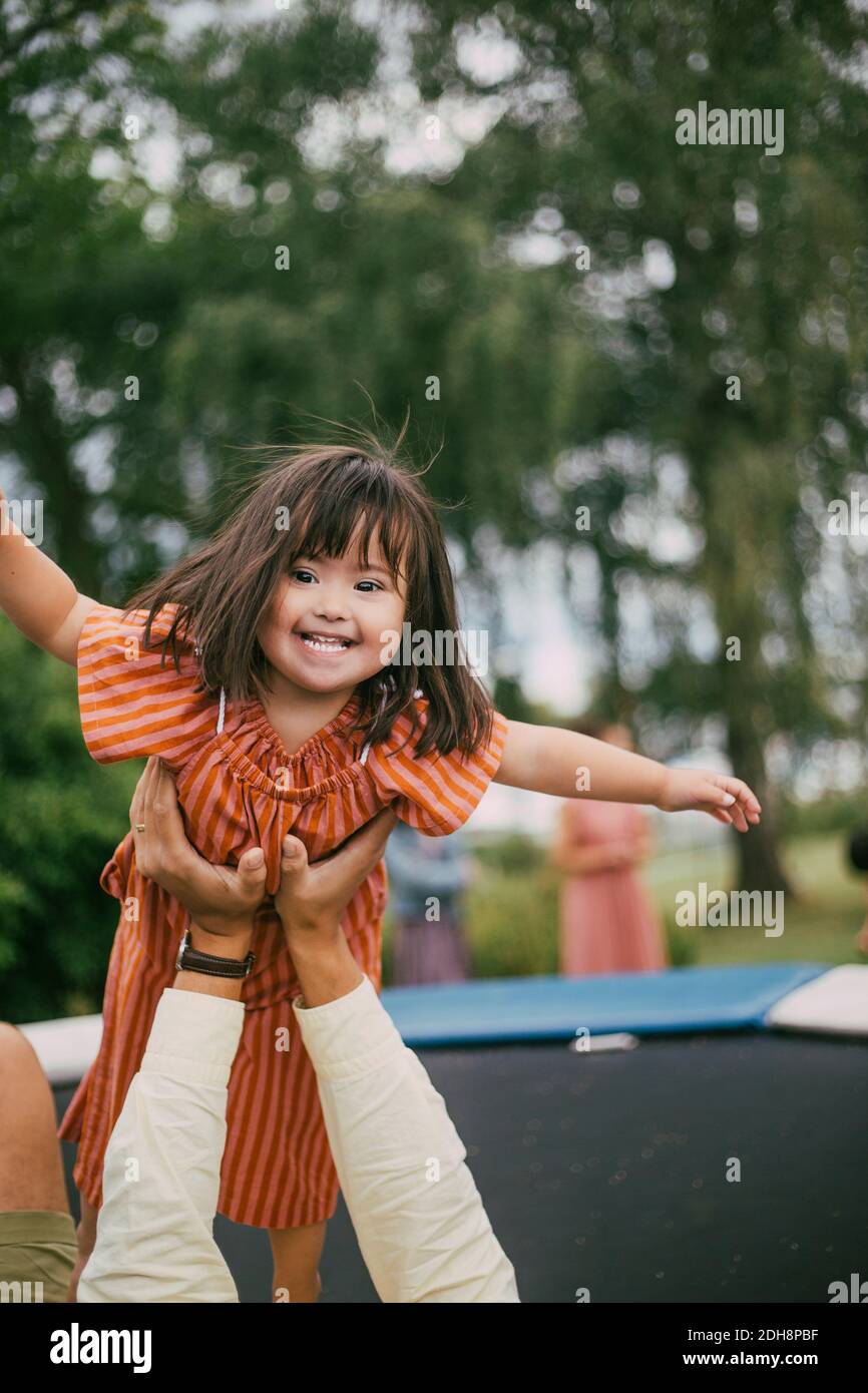 Portrait der lächelnden Down-Syndrom Tochter spielt mit Vater auf Trampolin im Sommer Stockfoto