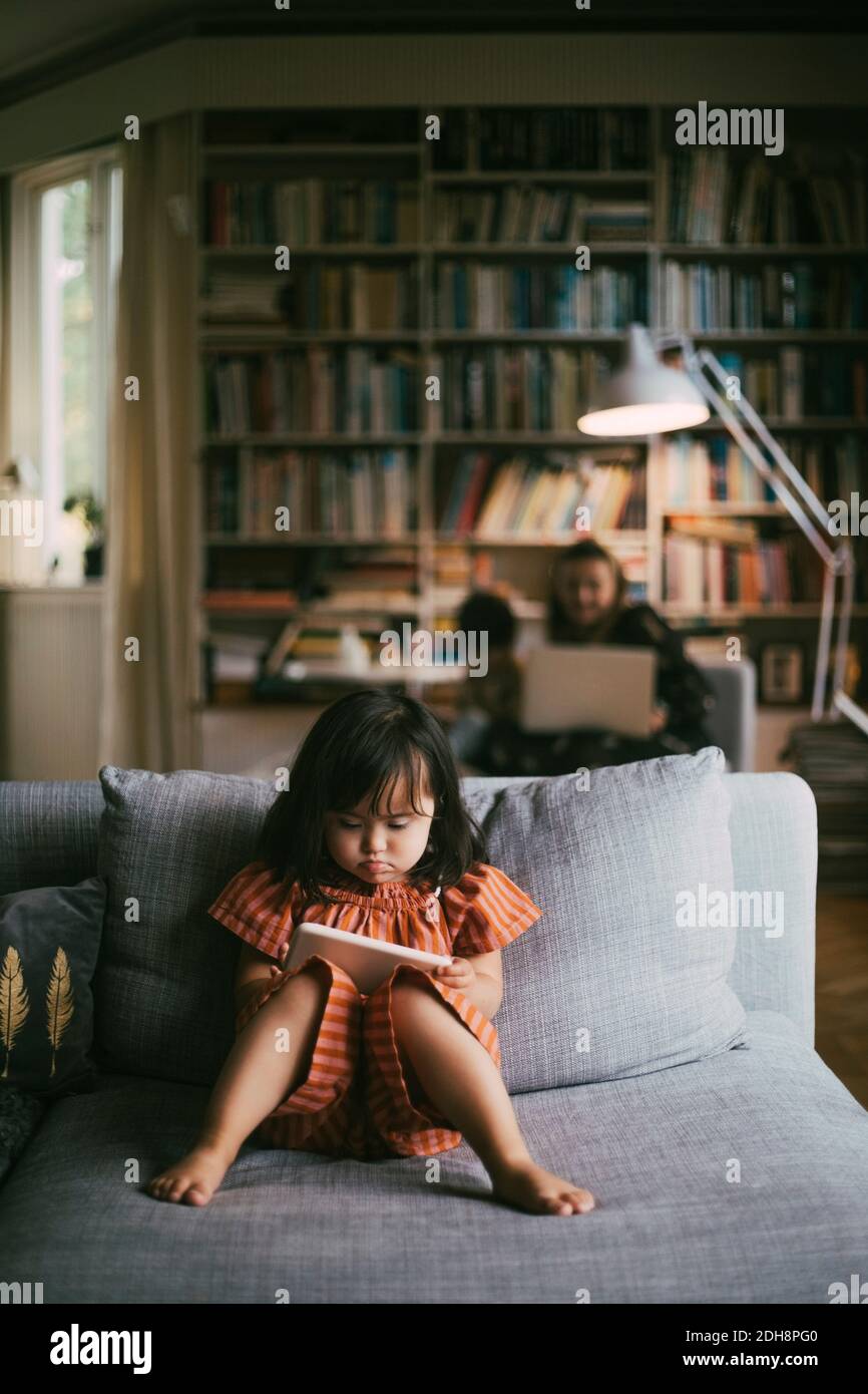 Down-Syndrom Mädchen mit Handy auf dem Sofa zu Hause Stockfoto