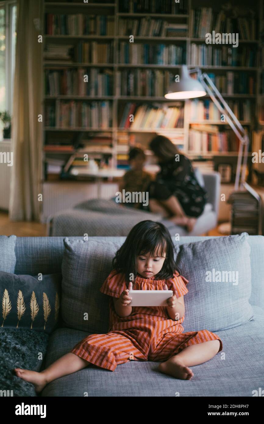 Down-Syndrom Mädchen mit Smartphone auf Sofa zu Hause Stockfoto