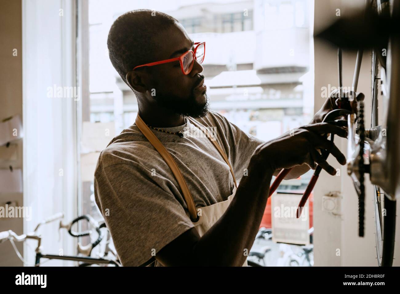 Männlicher Besitzer mit Handwerkzeug Reparatur Fahrrad in der Werkstatt Stockfoto