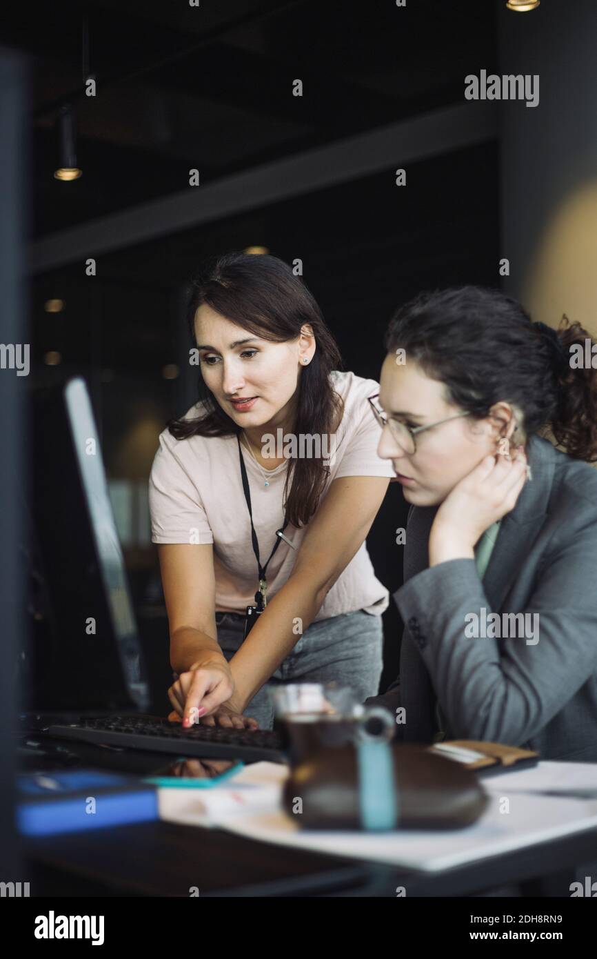 IT-Profi mit Kollegen, die im Büro an einem Laptop arbeiten Stockfoto