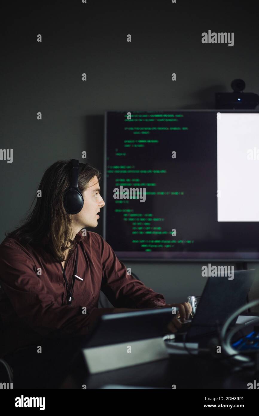 Betrachten SIE die PROFESSIONELLE IT-Arbeit, während Sie die Projektionsleinwand in betrachten Kreatives Büro Stockfoto