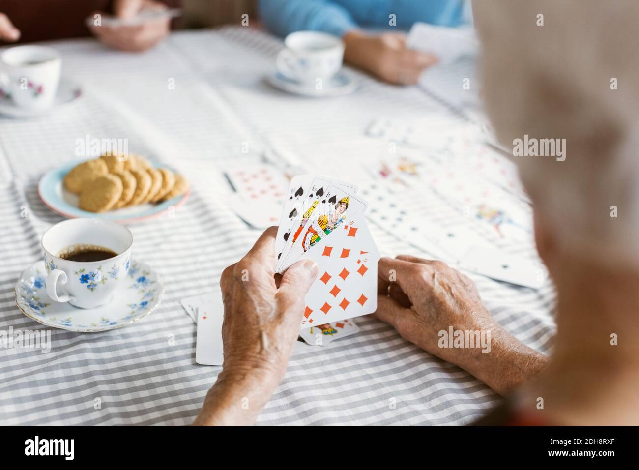 Zugeschnittenes Bild einer älteren Frau, die mit der Familie Karten spielt Tabelle Stockfoto