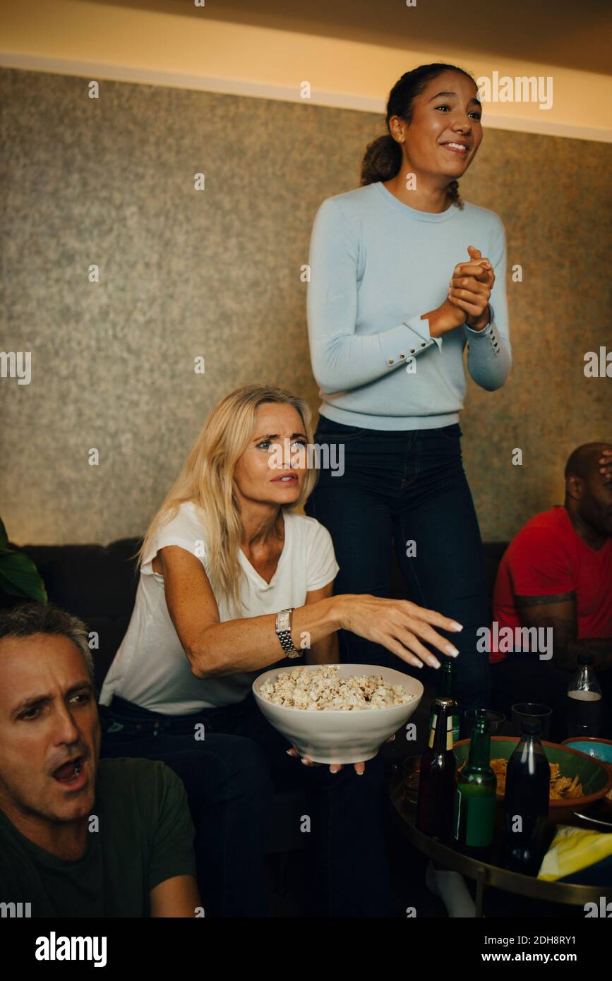 Aufgeregt Teenager mit Händen umklammert stehen bei der Familie während des Sports Ereignis Stockfoto