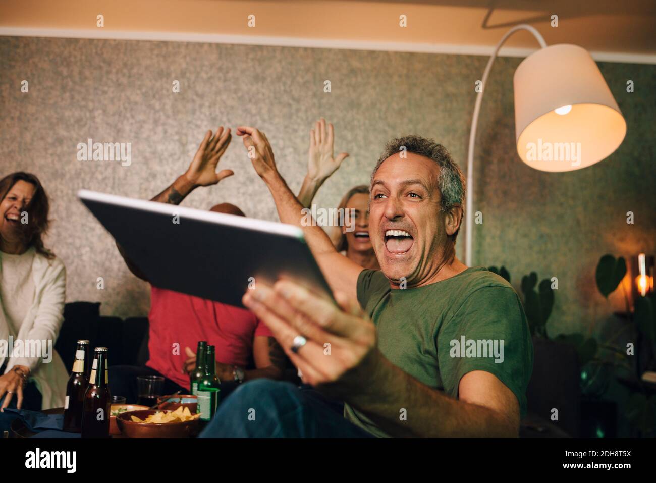 Aufgeregt Mann jubelte mit digitalen Tablet beim Sport zu beobachten Zu Hause Stockfoto