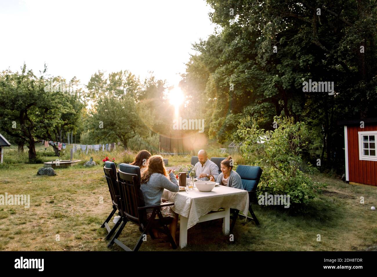 Lächelnde Familie genießen, während sie am Esstisch im Hof sitzen Stockfoto