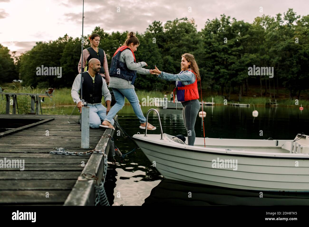 Eltern schauen auf Tochter, die die Hand der Schwester hält, während sie im Stehen stehen Boot über den See Stockfoto