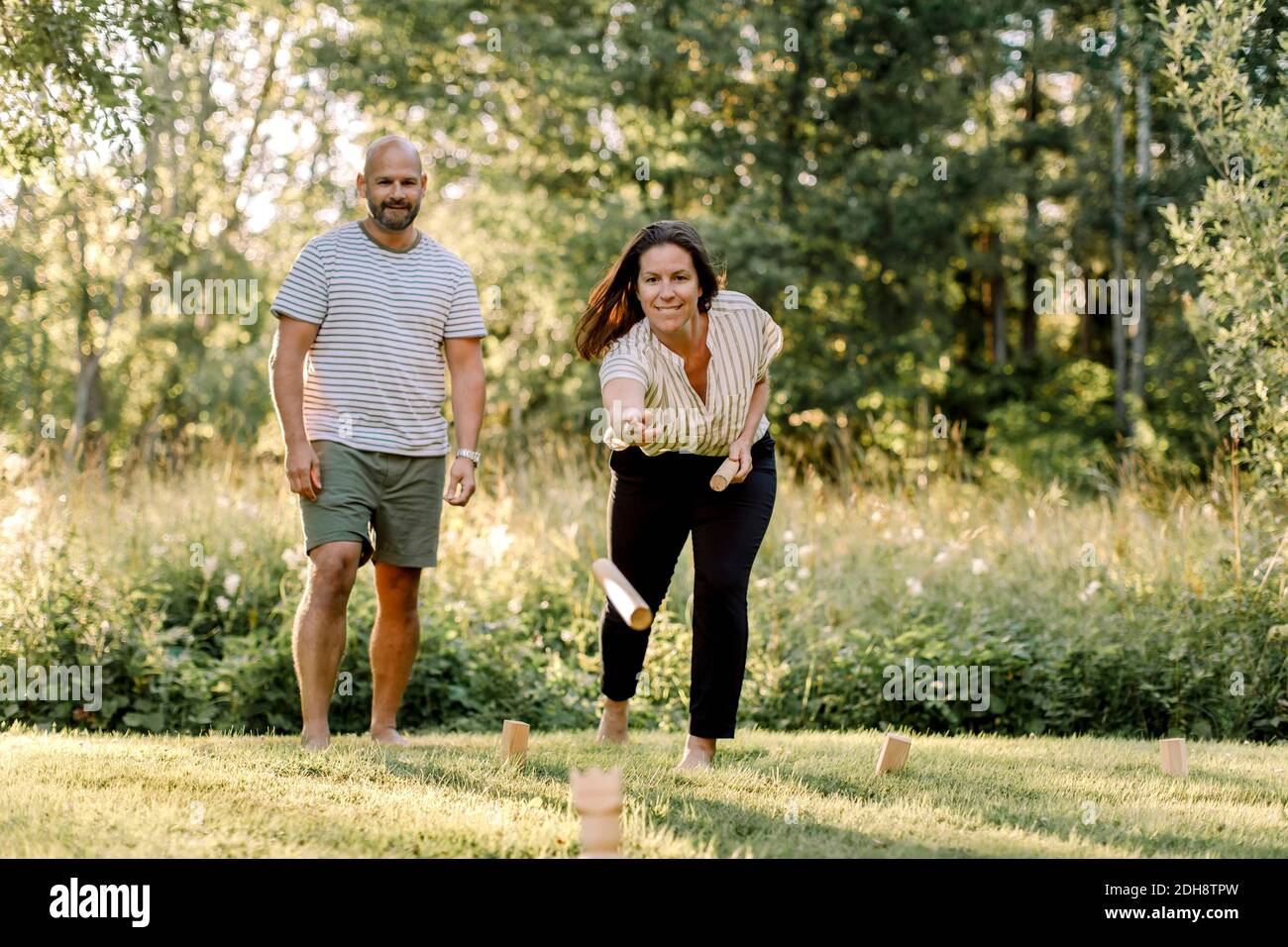 Lächelnde Frau mit männlichen Partner spielen molkky im Hof Stockfoto