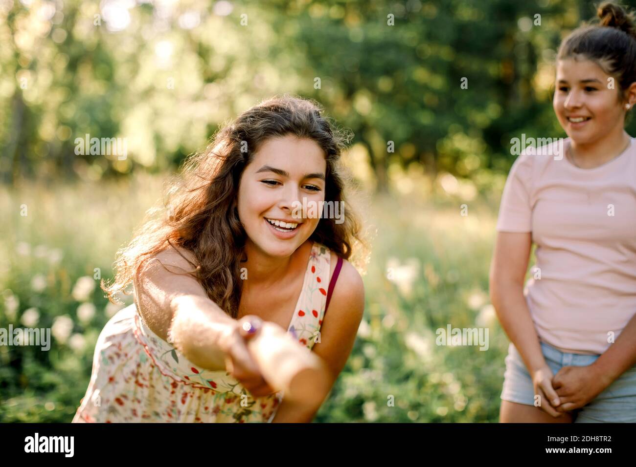 Lächelndes Mädchen, das Teenager-Geschwister ansieht, während sie molkky spielen Hinterhof Stockfoto