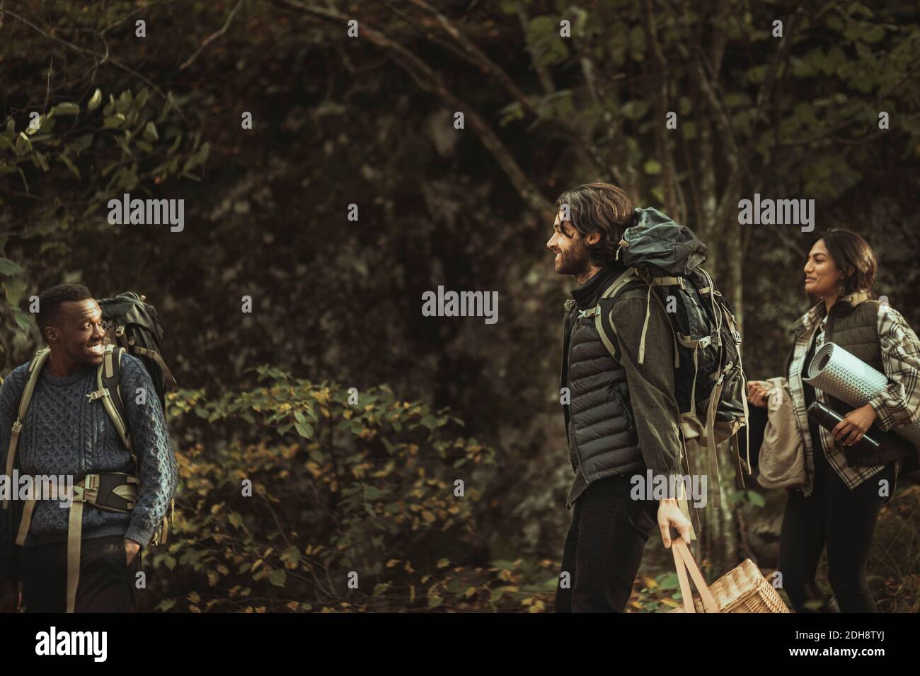 Lächelnde Freunde mit Rucksack reden im Wald während abenteuerlicher Reise Stockfoto