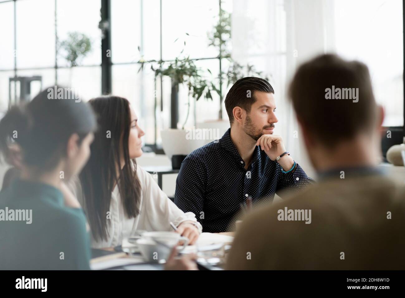 Seriöse Geschäftsleute, die in Meetings am Tisch sitzen Stockfoto