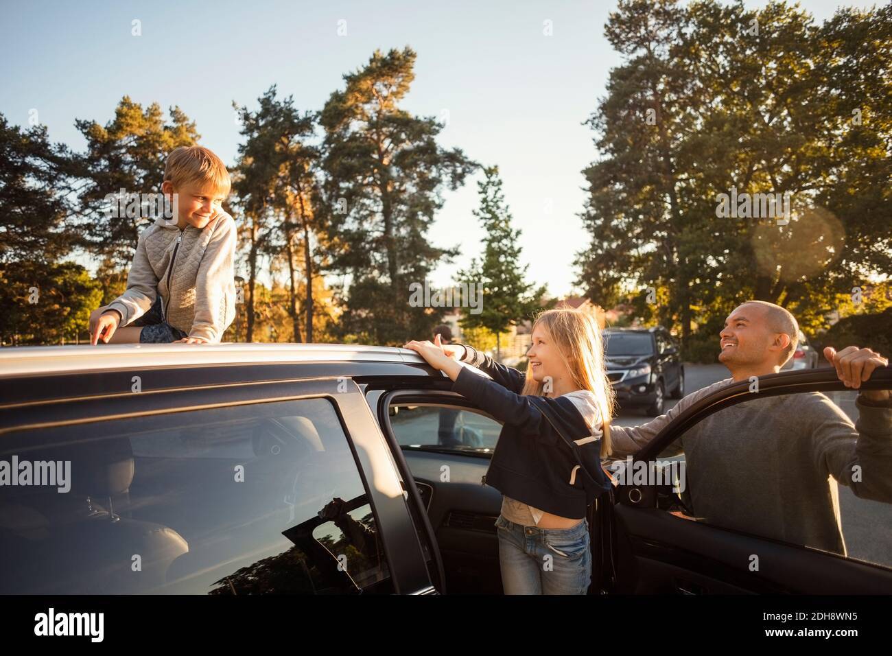 Glücklicher Vater und Tochter, die Jungen auf dem Auto sitzen Dach Stockfoto