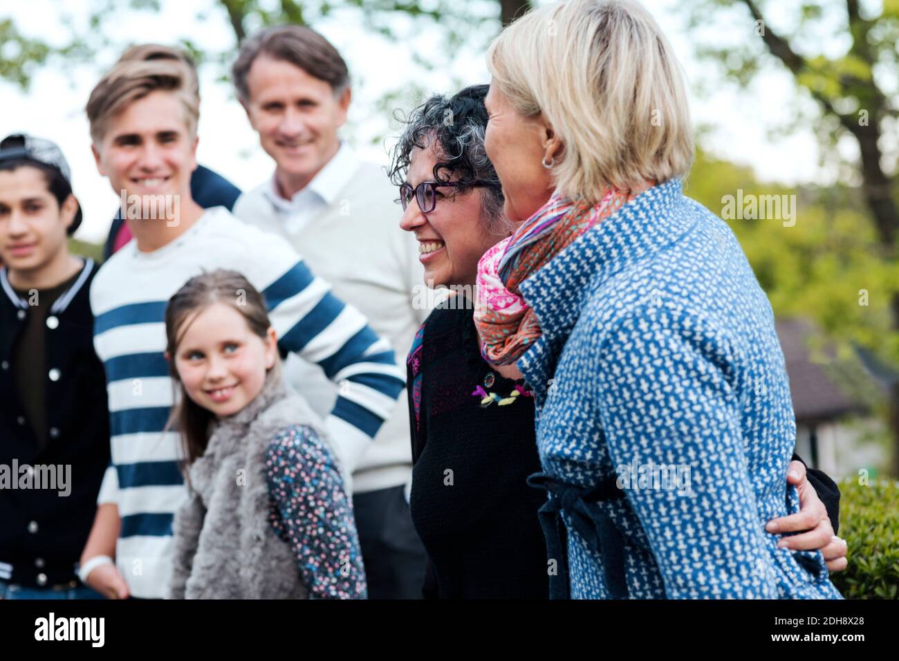 Lächelnde reife Frau mit Familie und Freunden auf dem Hof Stockfoto