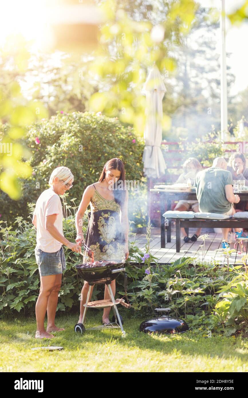 Reife Frauen Kochen Essen im Grill im Hinterhof während Gartenparty Stockfoto