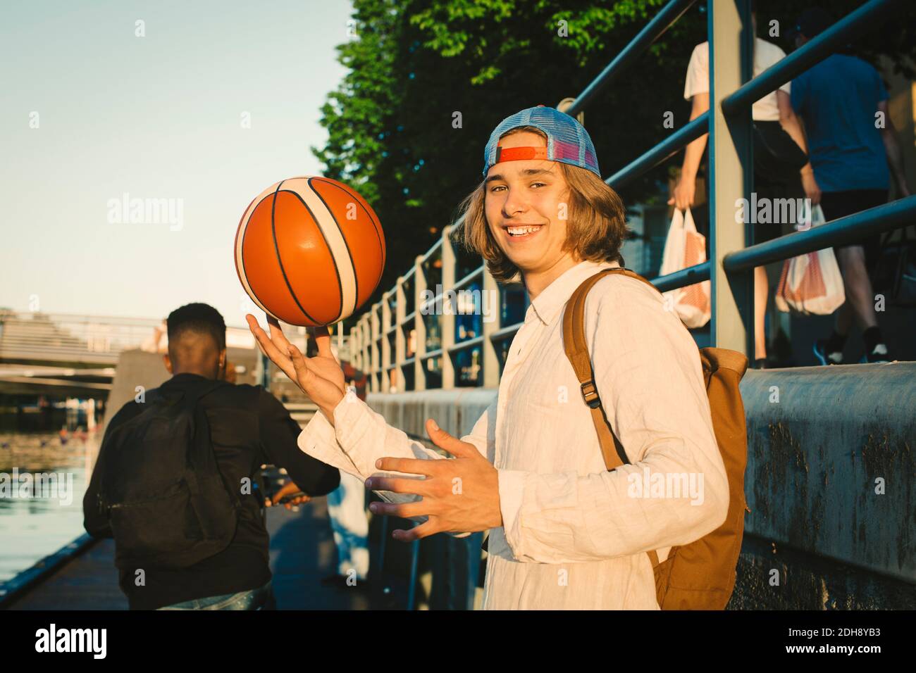 Porträt eines glücklichen Teenagers mit Basketball von einem Freund am Hafen Stockfoto