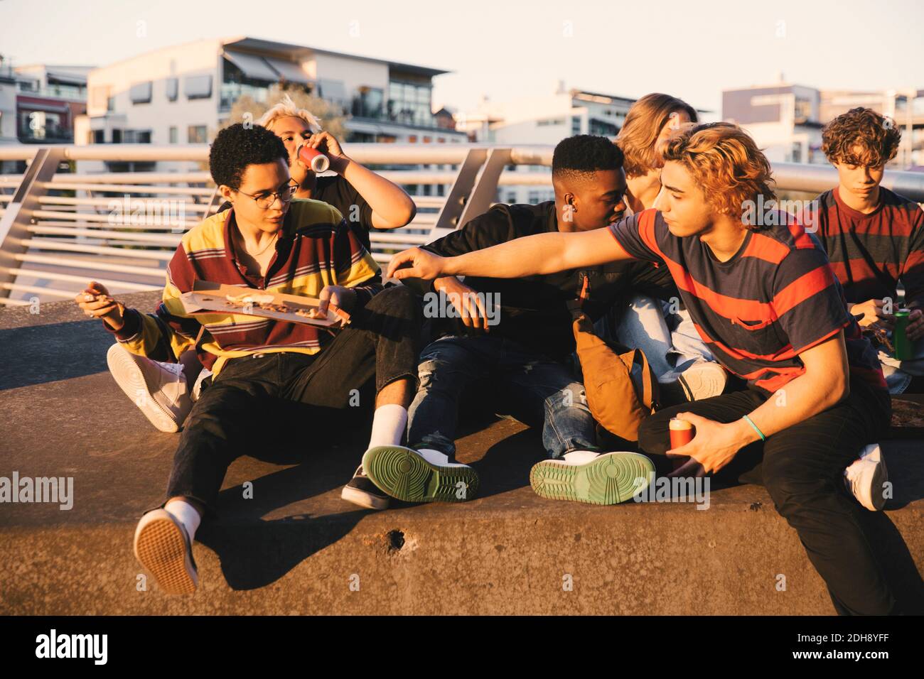 Junge und Teenager männliche Freunde genießen Pizza am Hafen in Stadt Stockfoto