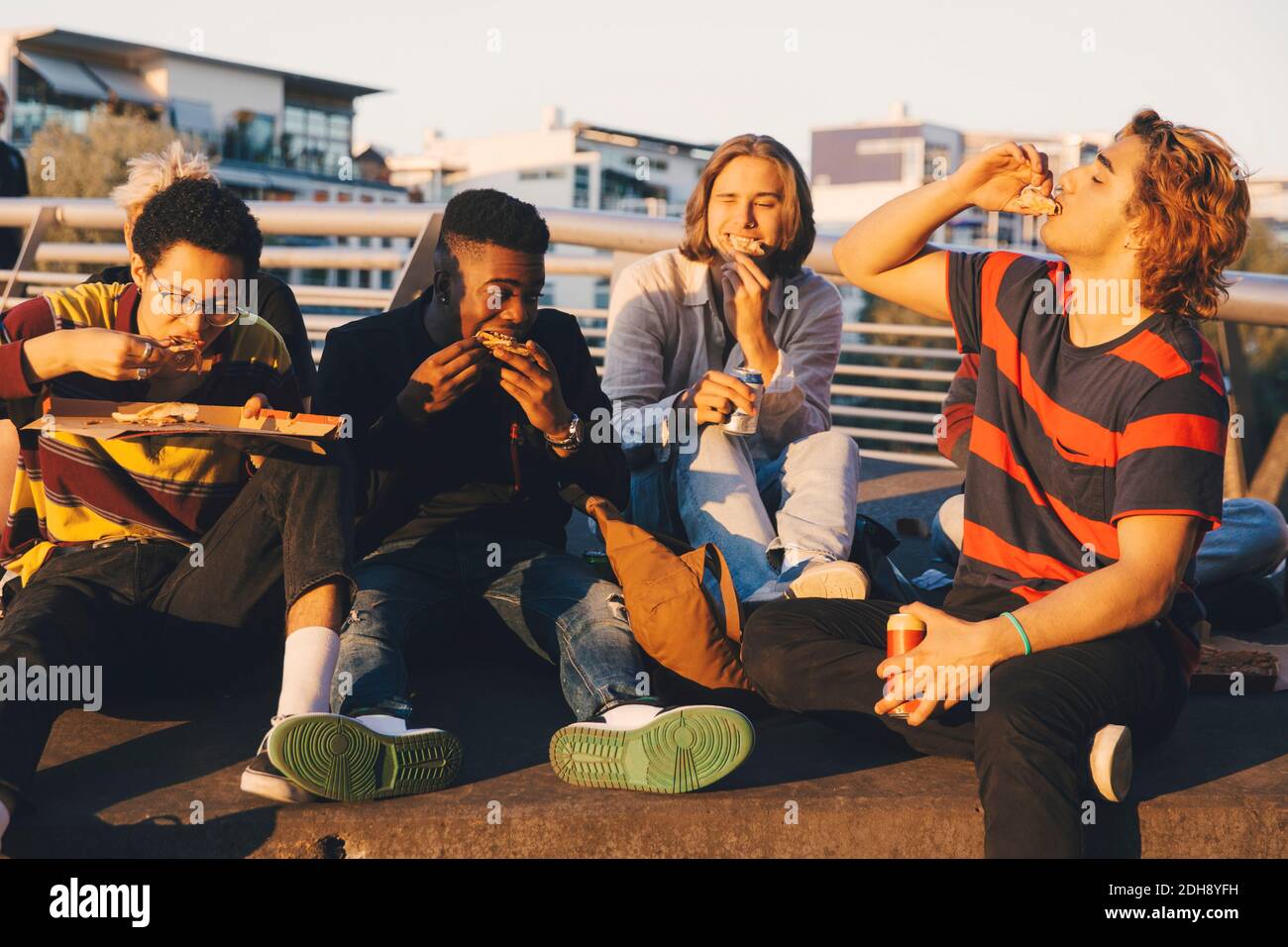Junge und Teenager männliche Freunde essen Pizza im Hafen in Stadt Stockfoto
