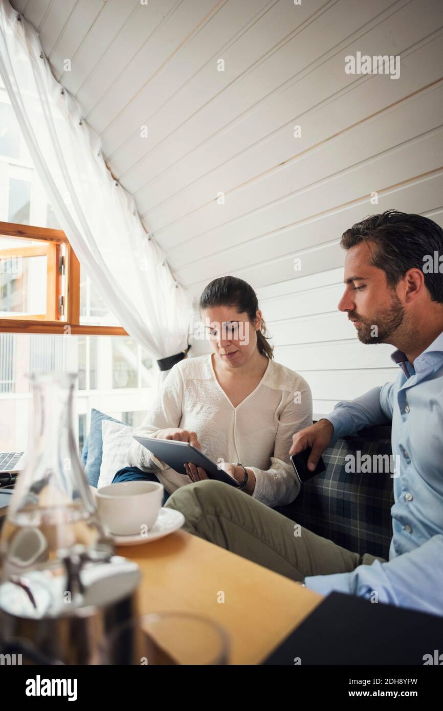 Mittelerwachsener Geschäftsmann mit weiblicher Kollegin, die ein digitales Tablet verwendet Büro Stockfoto
