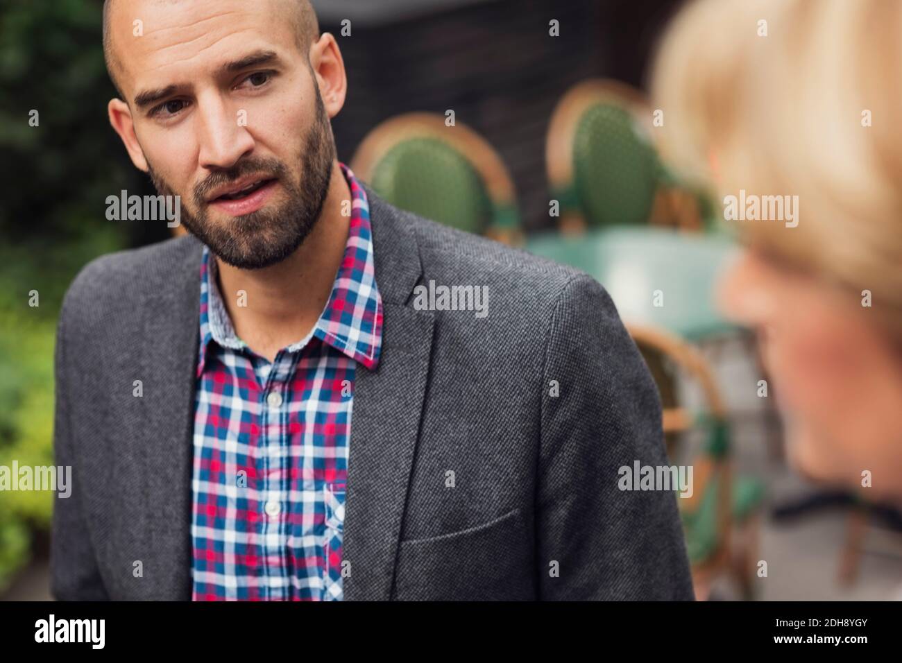 Mittelerwachsener Geschäftsmann im Gespräch mit einer Kollegin im Bürogebäude Stockfoto