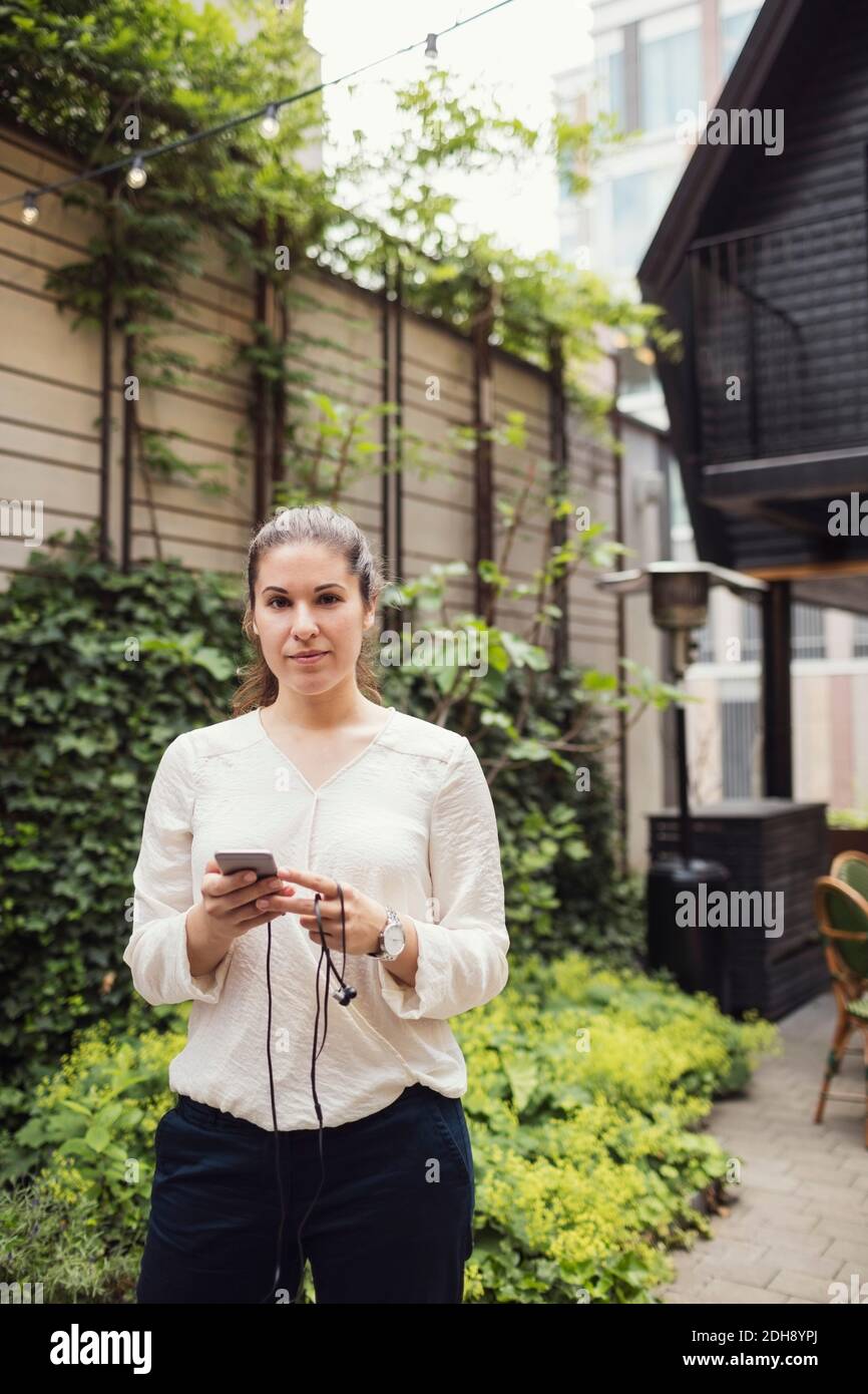 Porträt der selbstbewussten Geschäftsfrau hält Smartphone im Büro Hof Stockfoto