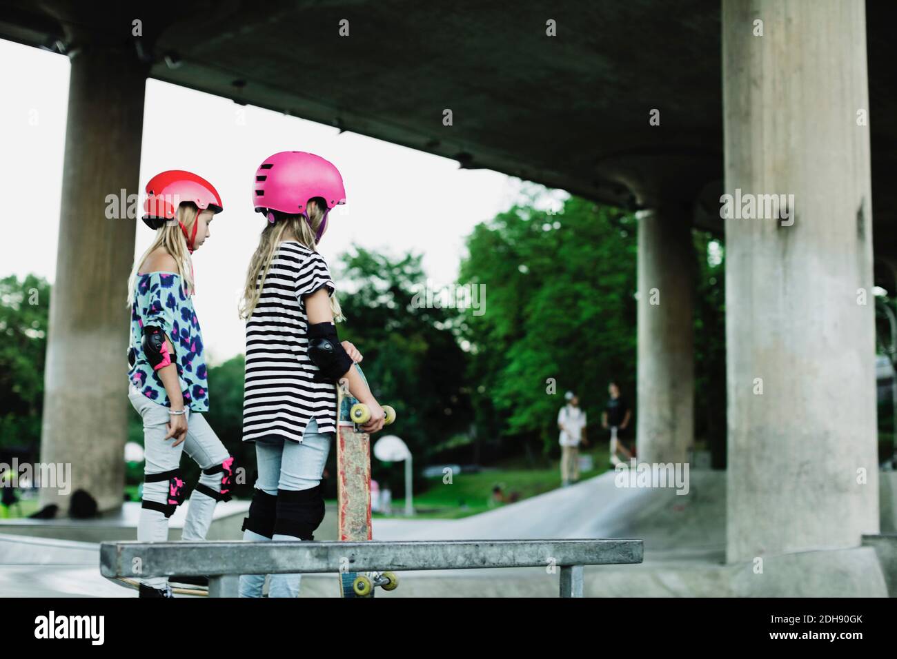 Freunde tragen Helme und Sicherheitspolster stehen im Skateboard Park Stockfoto