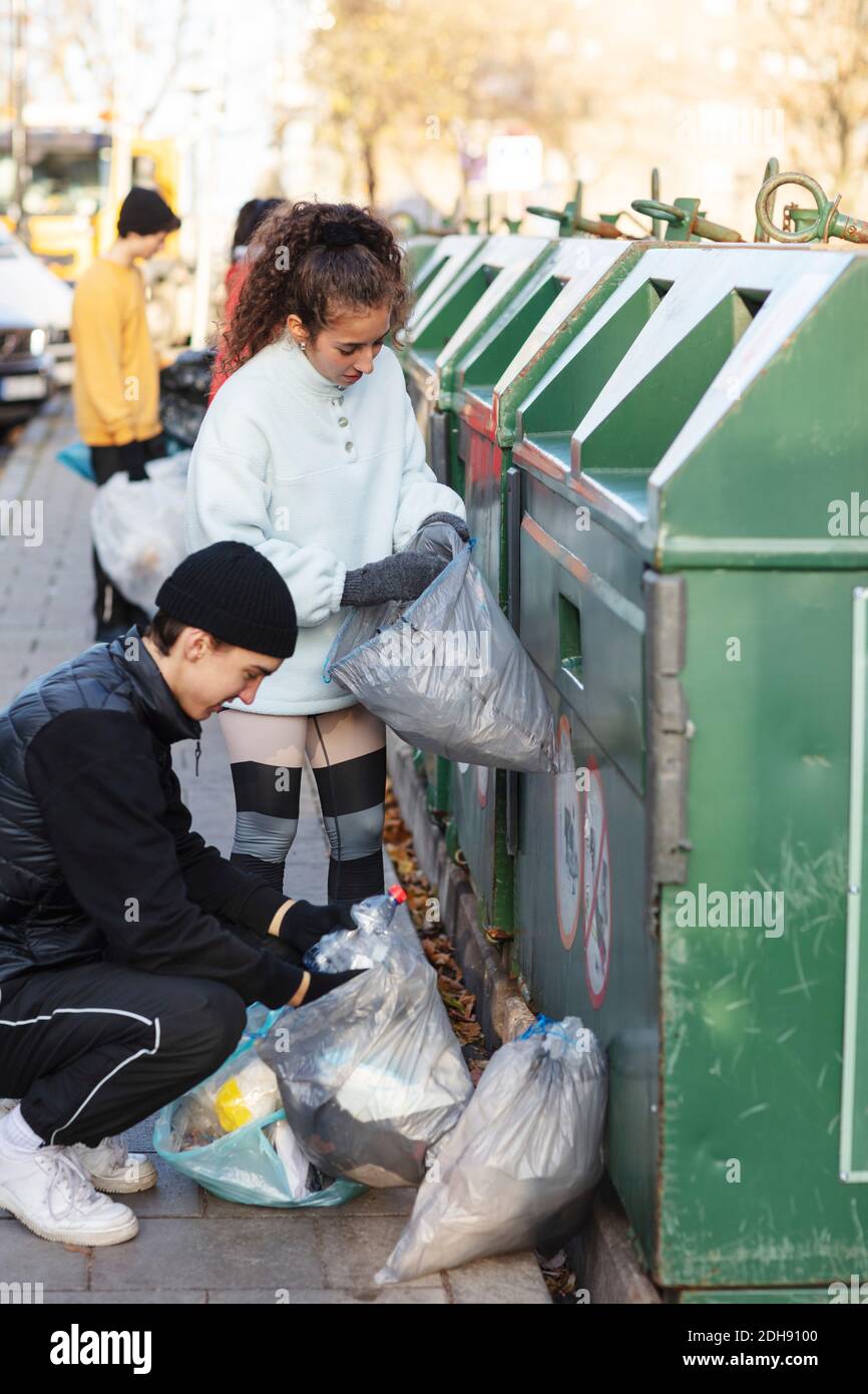 Junge männliche und weibliche Umweltschützer werfen Recycling-Abfall in Müll Kann Stockfoto