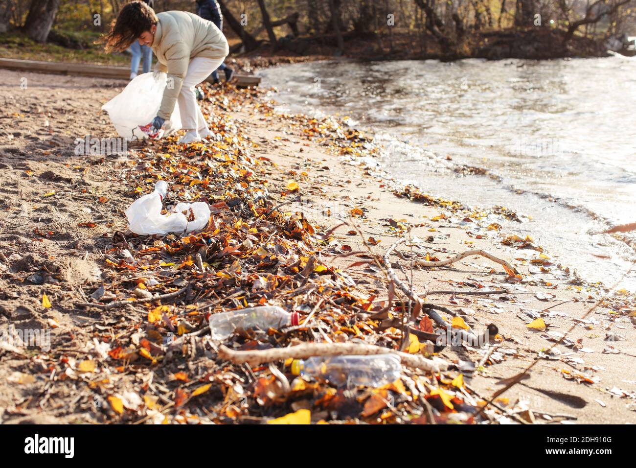 Weibliche Freiwillige sammeln Plastikmüll am See Stockfoto