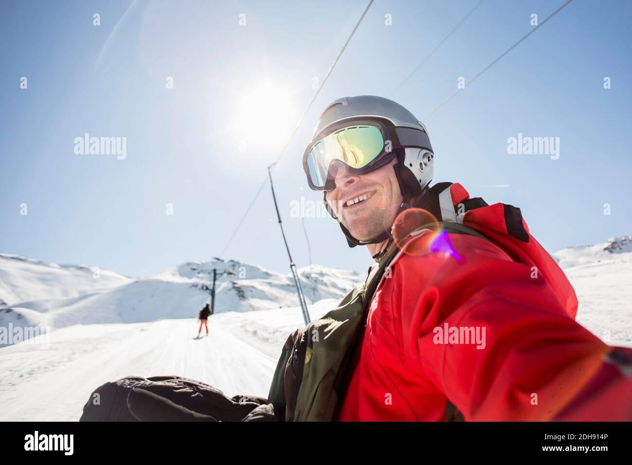 Lächelnder Mann in Skibekleidung auf schneebedecktem Feld gegen klar Himmel Stockfoto