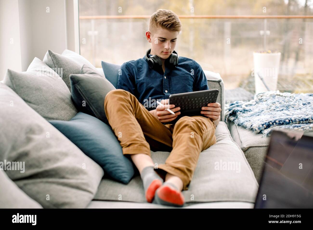 Teenager mit digitalem Tablet, während sie auf dem Sofa sitzen Zu Hause Stockfoto